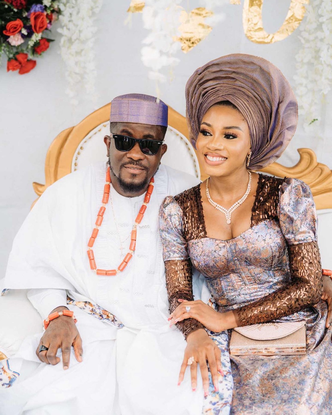A couple seated together in traditional dress and coral beads at their engagement ceremony