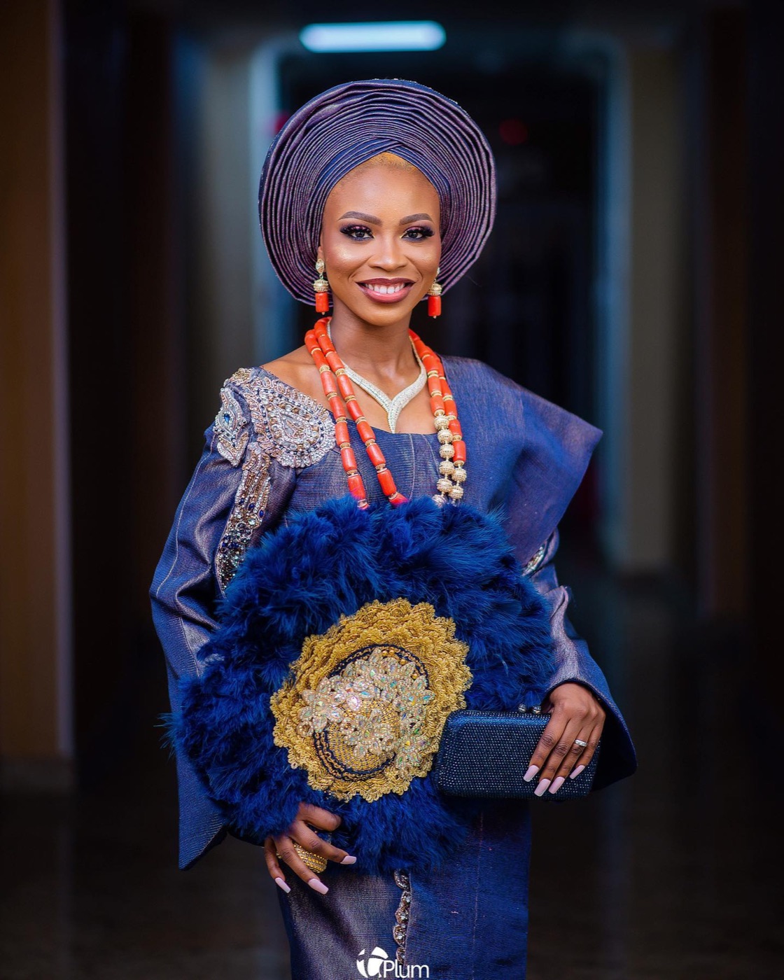 A bride in navy and gold beaded aso-oke, seated portrait