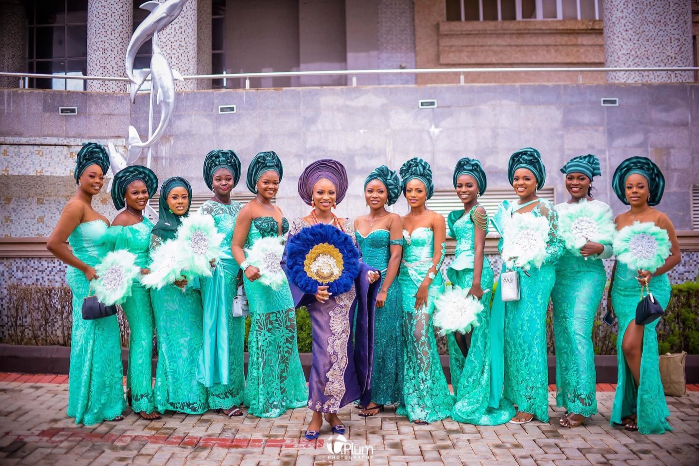 Bridesmaids in coordinated emerald aso-ebi and matching headwraps, celebrating outdoors