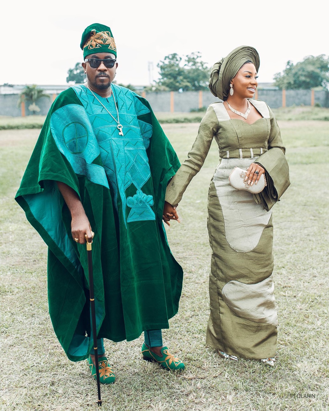 A couple in matching emerald and olive traditional dress, walking together outdoors